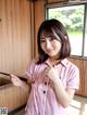 A woman in a pink and white striped shirt holding a knife.