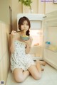 A woman sitting on the floor eating a bowl of noodles.