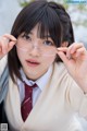 A woman in a school uniform holding up a pair of glasses.