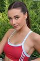 A woman in a red and white sports bra posing for a picture.