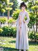 A woman in a white kimono standing in a park.