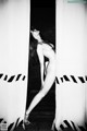 A naked woman standing in front of a white curtain.