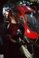 A woman in a red dress sitting on a motorcycle.