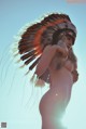 A naked woman wearing an indian headdress poses for a picture.