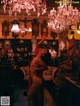 A naked woman standing in a room with a chandelier.