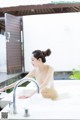 A naked woman sitting in a bathtub with a faucet.