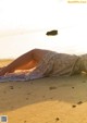 A woman laying on a blanket on the beach.