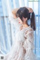 A woman in a white dress sitting on a window sill.