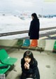 A woman sitting on a bench next to a train track.