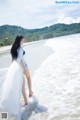A woman in a white dress standing in the water.