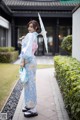 A woman in a blue and pink kimono holding an umbrella.