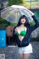 A woman in a green bikini holding an umbrella.