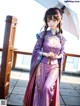 A woman in a purple dress holding an umbrella.