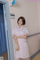 A woman in a white nurse uniform standing in a room.