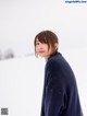 A woman standing in the snow wearing a blue sweater.