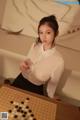 a woman in a white shirt and black skirt playing a game of checkers