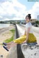 A woman sitting on a concrete wall next to the ocean.