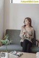 A woman sitting on a couch holding a glass of water.