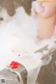 A woman taking a bath in a bathtub filled with foam.