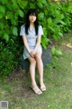 A woman sitting on a rock in the grass.