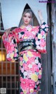 A woman in a pink and black kimono posing for a picture.