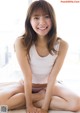 A young woman sitting on a bed smiling at the camera.