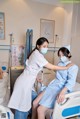 A nurse helping a patient in a hospital bed.