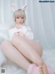 A woman in a bunny costume sitting on a white fur rug.