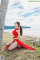 A woman in a red dress sitting on the ground.