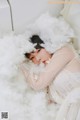 A woman in a white dress laying on a bed covered in clouds.