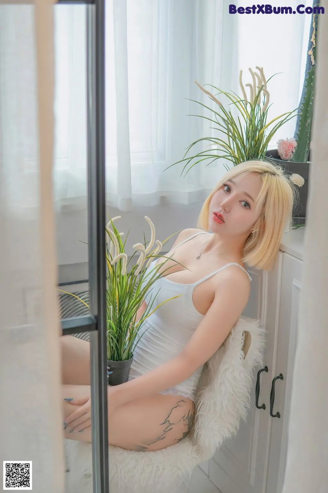 A woman sitting on a chair in front of a window.