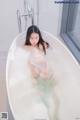 A woman sitting in a bathtub filled with foam.