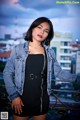 A woman in a black dress and denim jacket posing for a picture.