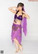 A woman in a purple belly dance outfit posing for a picture.