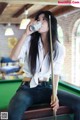 A woman sitting on a pool table drinking from a can.