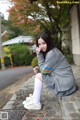 A woman sitting on a stone wall holding a flower.