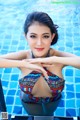 A woman in a colorful bikini sitting in a pool.