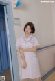 a woman in a white uniform standing in front of a door