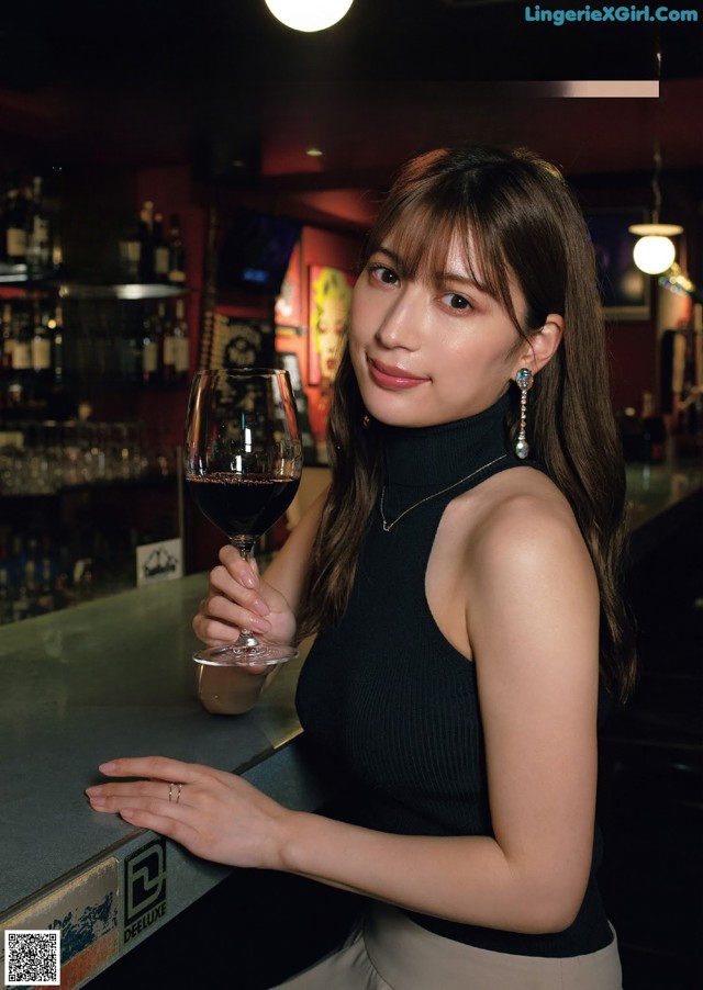 A woman holding a glass of wine at a bar.